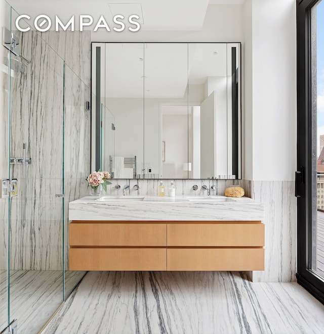 bathroom with double vanity, a marble finish shower, and a sink