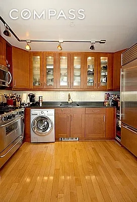 kitchen with dark countertops, washer / clothes dryer, stainless steel appliances, and a sink