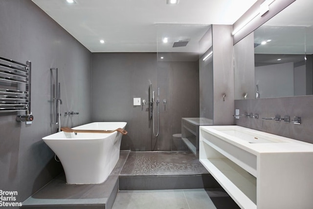 full bath with visible vents, a walk in shower, radiator heating unit, a freestanding bath, and vanity