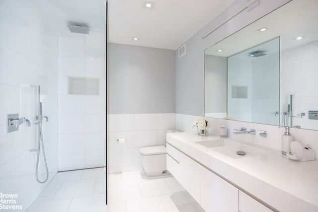 bathroom featuring a walk in shower, tile patterned flooring, vanity, toilet, and tile walls