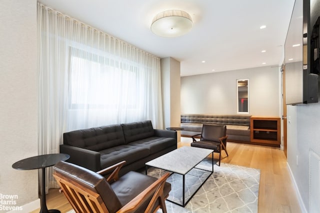 living area with recessed lighting, baseboards, and light wood-style flooring