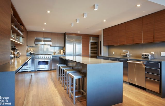10 W 66th St Unit 22Abc, New York City, NY 10023 - kitchen with premium appliances, beverage cooler, ventilation hood, modern cabinets, and light wood-type flooring
