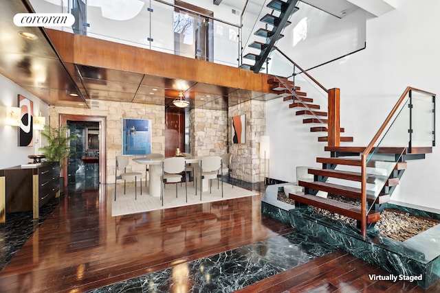 stairway with wood-type flooring and a high ceiling