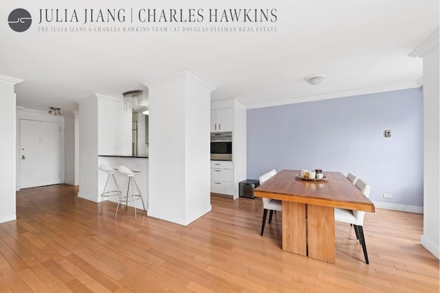 dining space with ornamental molding and light hardwood / wood-style floors