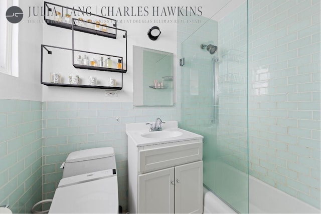 full bathroom featuring tile walls, vanity, toilet, and combined bath / shower with glass door