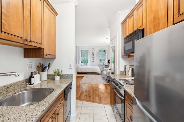 kitchen with appliances with stainless steel finishes, brown cabinetry, open floor plan, light tile patterned flooring, and a sink