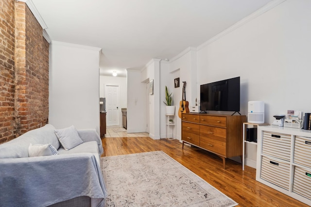 living room featuring baseboards, brick wall, ornamental molding, and wood finished floors