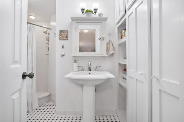 full bath with a tile shower and baseboards
