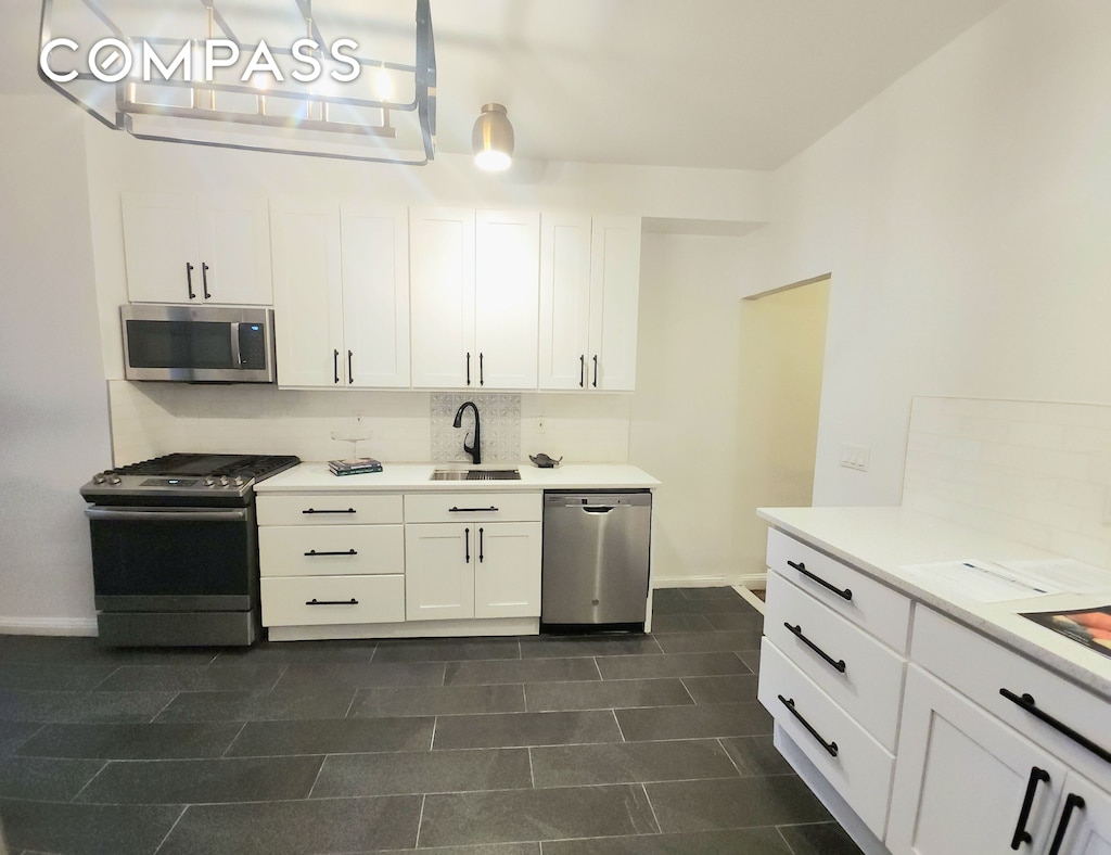 111 W 96th St Unit 10, New York City, NY 10025 - kitchen with appliances with stainless steel finishes, a sink, baseboards, light countertops, and white cabinetry