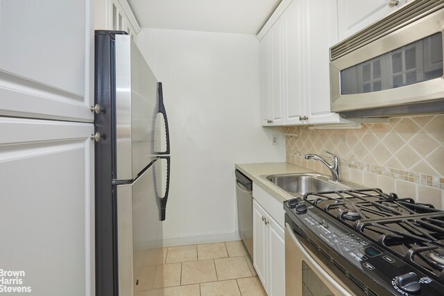 kitchen with tasteful backsplash, stainless steel appliances, sink, and white cabinets