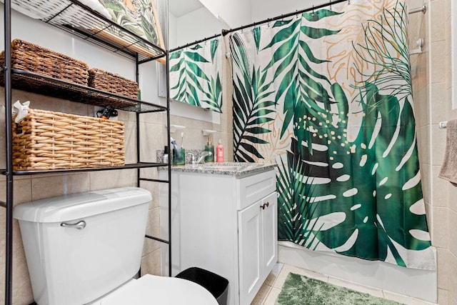 bathroom with tile walls, toilet, and vanity