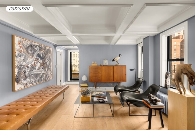 living area with a healthy amount of sunlight, coffered ceiling, beam ceiling, and light wood-type flooring