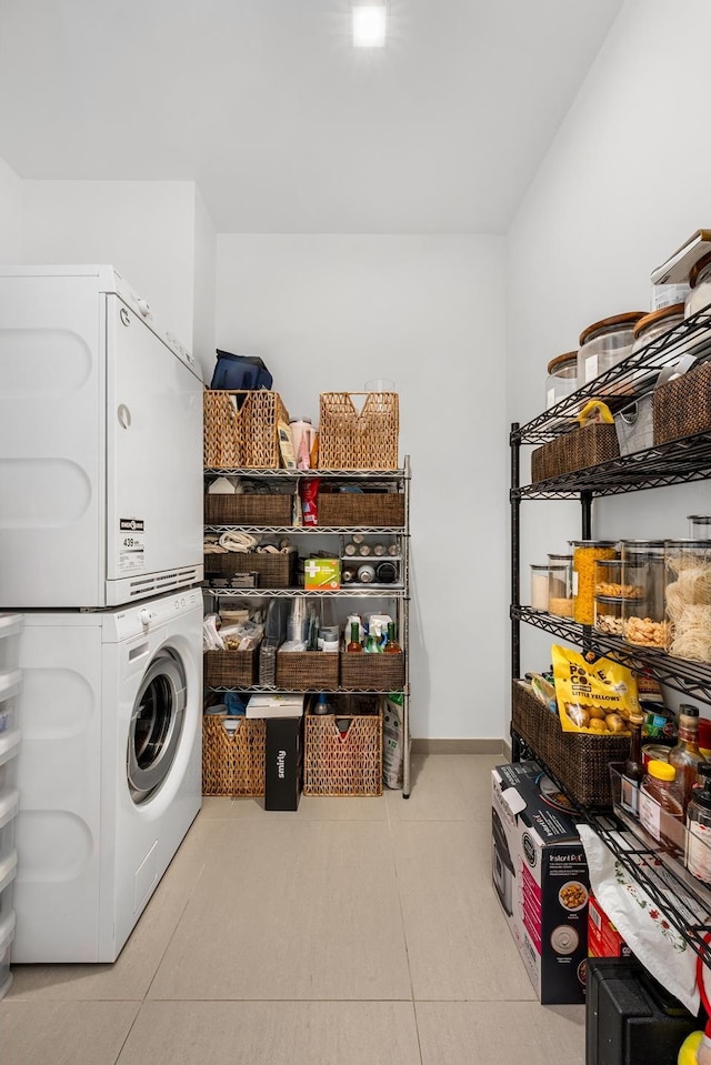 washroom featuring stacked washing maching and dryer, tile patterned flooring, and laundry area