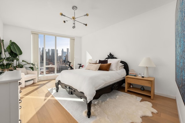 bedroom featuring light wood-style floors, baseboards, a city view, and access to exterior