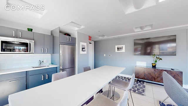 171 W 131st St Unit 620, New York City, NY 10027 - kitchen with stainless steel appliances, a sink, a breakfast bar, light countertops, and decorative backsplash