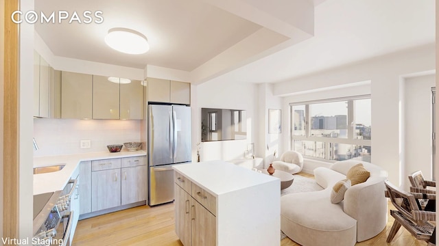 kitchen with light wood finished floors, stainless steel appliances, light countertops, cream cabinetry, and open floor plan