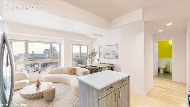 living area featuring a city view, light wood-style flooring, recessed lighting, and baseboards