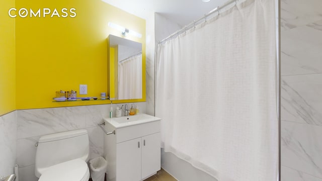 bathroom featuring shower / bathtub combination with curtain, toilet, tile walls, and vanity