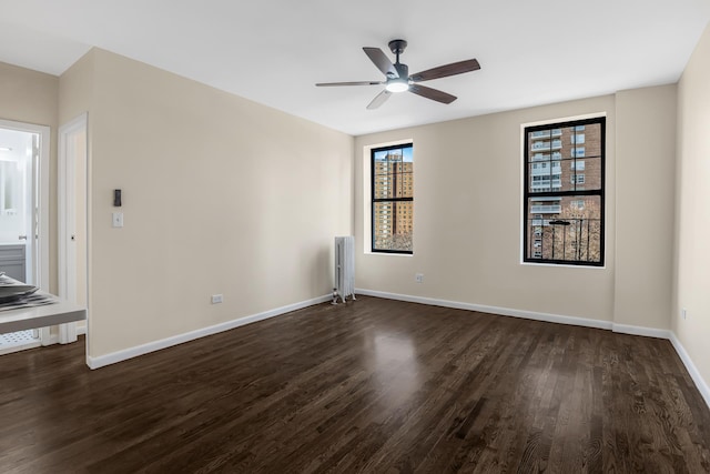 empty room with a ceiling fan, baseboards, and dark wood-style flooring