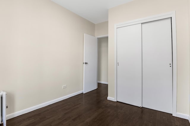 unfurnished bedroom with baseboards, dark wood finished floors, and a closet