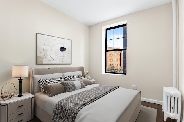 bedroom with dark wood-style flooring, radiator, and baseboards