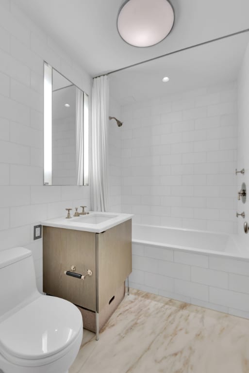 full bathroom featuring vanity, tile walls, shower / tub combo, and toilet