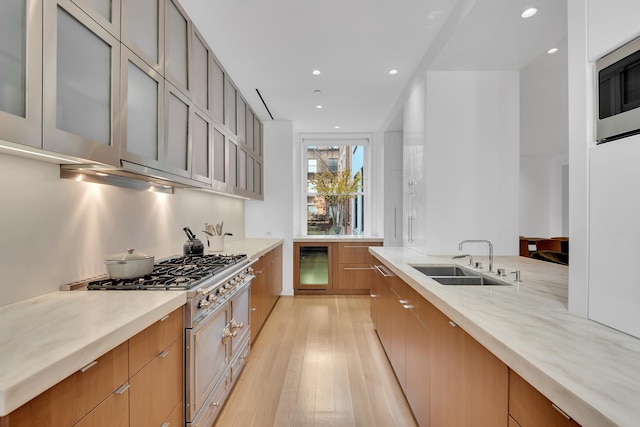 kitchen featuring light wood finished floors, a sink, stainless steel microwave, recessed lighting, and modern cabinets