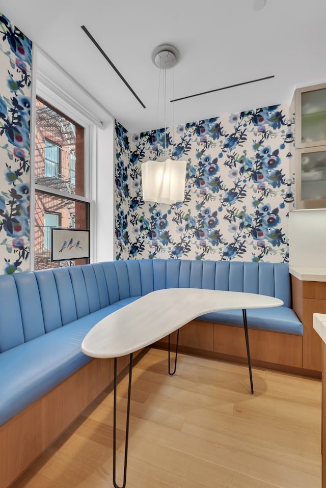 interior space with breakfast area, wallpapered walls, and light wood-style flooring