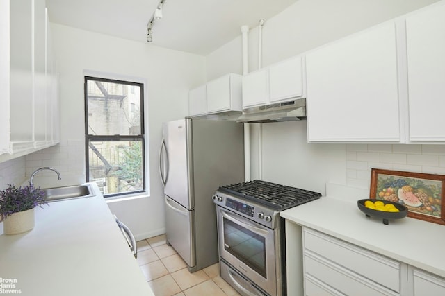 kitchen with sink, white cabinetry, light tile patterned floors, appliances with stainless steel finishes, and a wealth of natural light