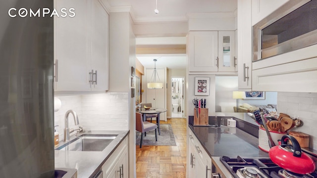 kitchen with ornamental molding, decorative backsplash, stainless steel appliances, white cabinets, and a sink