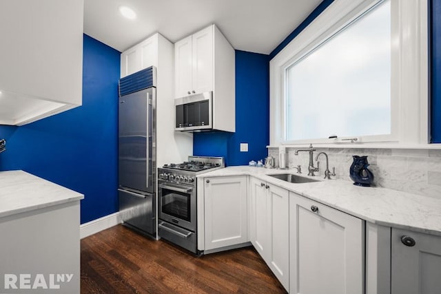 kitchen with sink, white cabinetry, dark hardwood / wood-style floors, high quality appliances, and tasteful backsplash