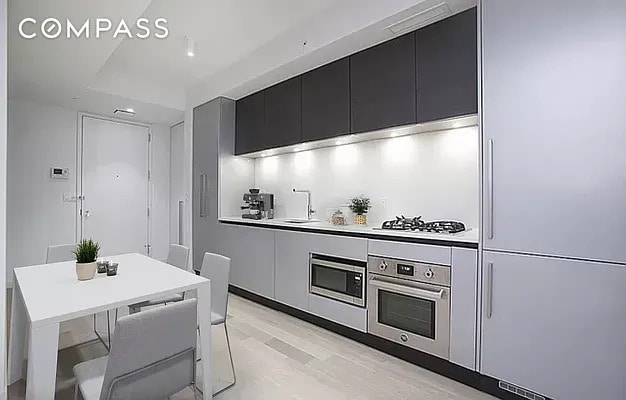 540 W 49th St Unit 406N/407N, New York City, NY 10019 - kitchen featuring built in appliances, dark cabinets, modern cabinets, and light countertops