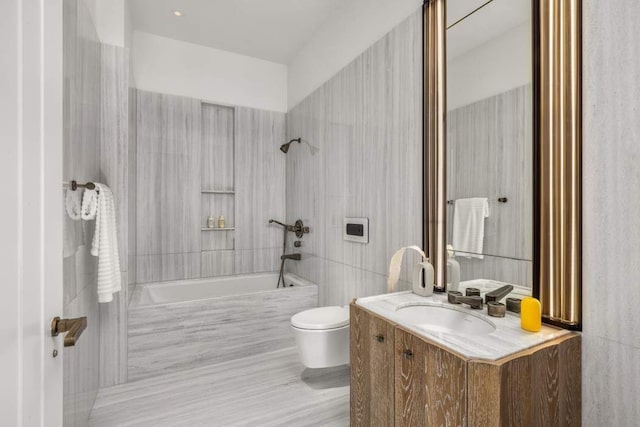 full bathroom with tiled shower / bath, vanity, toilet, and tile walls