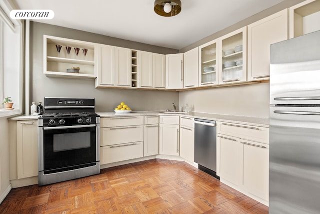 kitchen with white cabinetry, sink, light parquet flooring, and appliances with stainless steel finishes