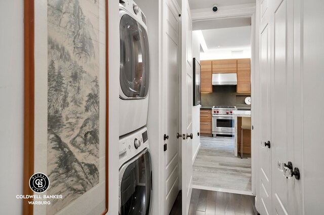 laundry room with stacked washer / drying machine and wood-type flooring