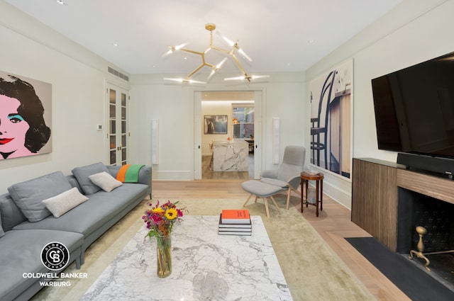 living room featuring french doors, a chandelier, and light hardwood / wood-style flooring