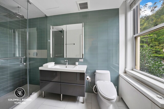 bathroom featuring walk in shower, plenty of natural light, tile walls, and vanity