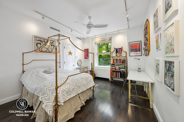 bedroom featuring rail lighting and dark hardwood / wood-style floors