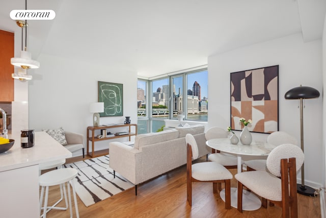 living area featuring a view of city, visible vents, light wood-style flooring, and expansive windows