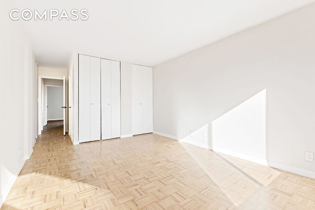 unfurnished bedroom with two closets and light parquet flooring