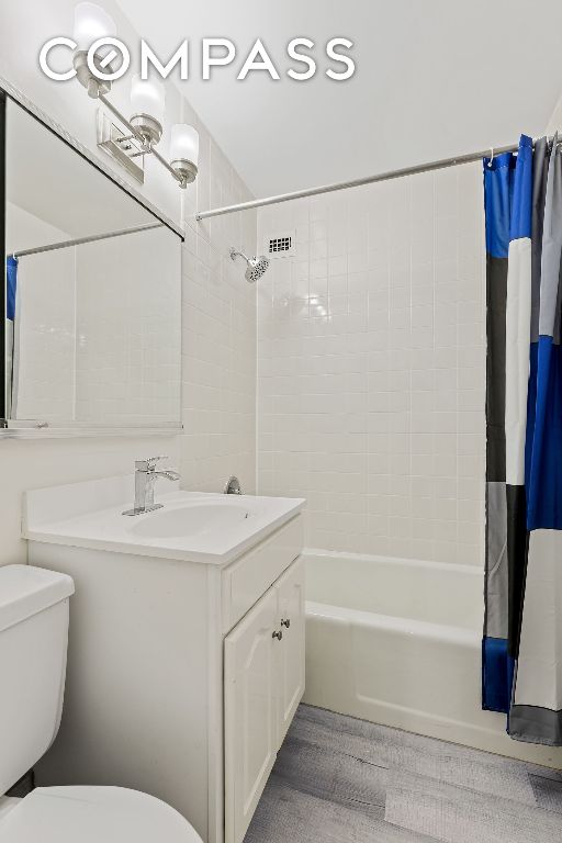 full bathroom with shower / bathtub combination with curtain, vanity, and toilet