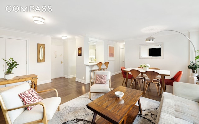 living area with ornamental molding, wood finished floors, and baseboards