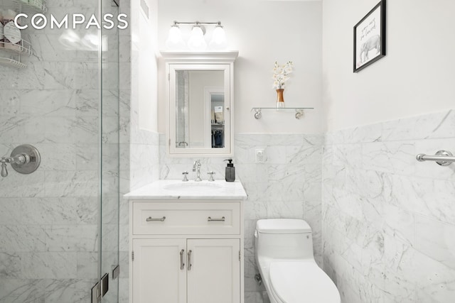 bathroom featuring tile walls, a stall shower, vanity, a wainscoted wall, and toilet