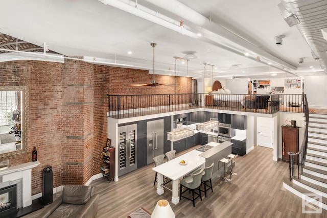 living room with a glass covered fireplace, stairway, wood finished floors, and brick wall