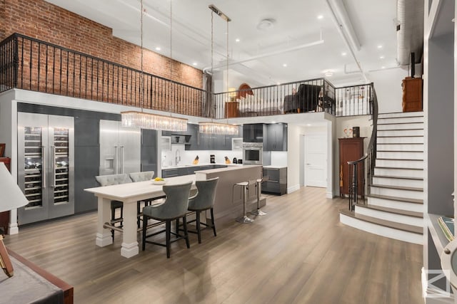 dining area with stairway, beverage cooler, light wood-style flooring, and a high ceiling