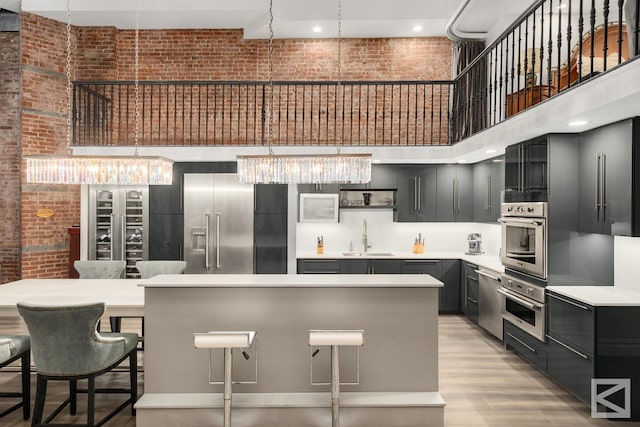 kitchen featuring a sink, dark cabinetry, appliances with stainless steel finishes, light countertops, and a towering ceiling