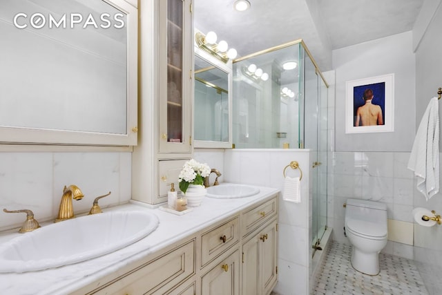 bathroom featuring a shower with shower door, tile walls, tile patterned flooring, vanity, and toilet