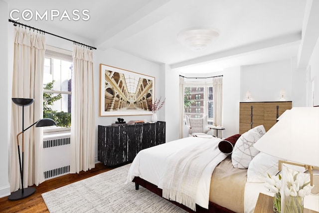 bedroom with beamed ceiling, radiator, and dark hardwood / wood-style floors