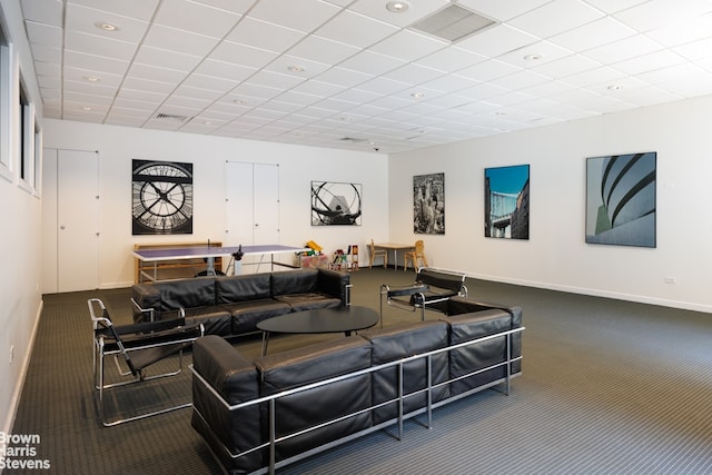 living room featuring a drop ceiling and dark colored carpet