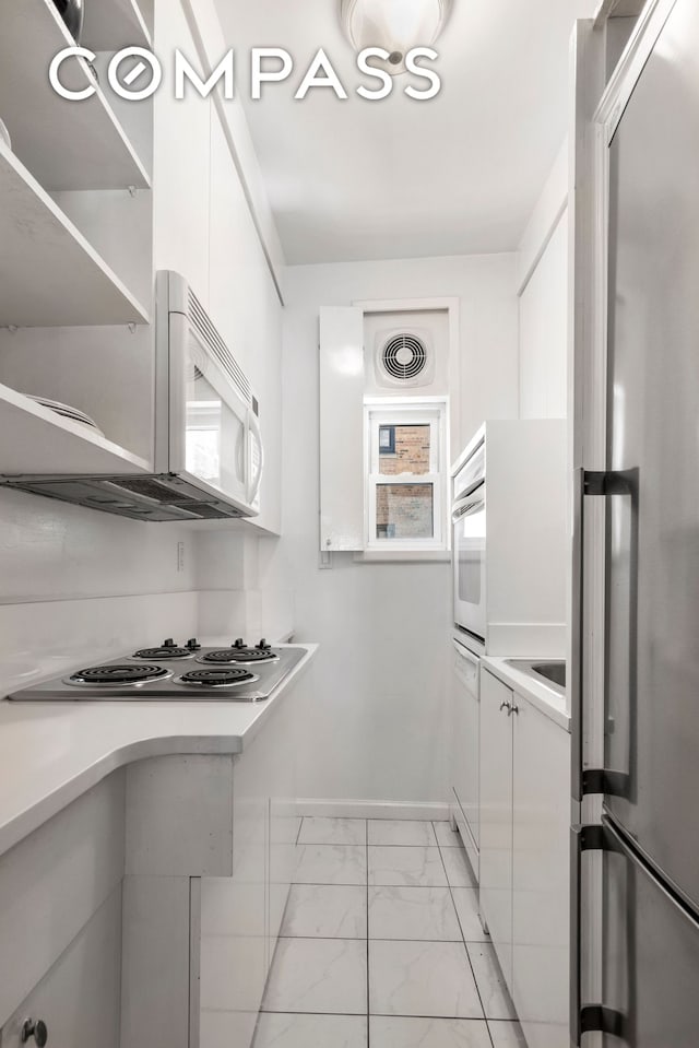 kitchen with marble finish floor, appliances with stainless steel finishes, white cabinets, and light countertops